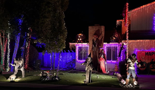 Halloween decorations at a house with two animatronic werewolves, a witch, spiders, and a 12-foot-tall pumpkinhead.